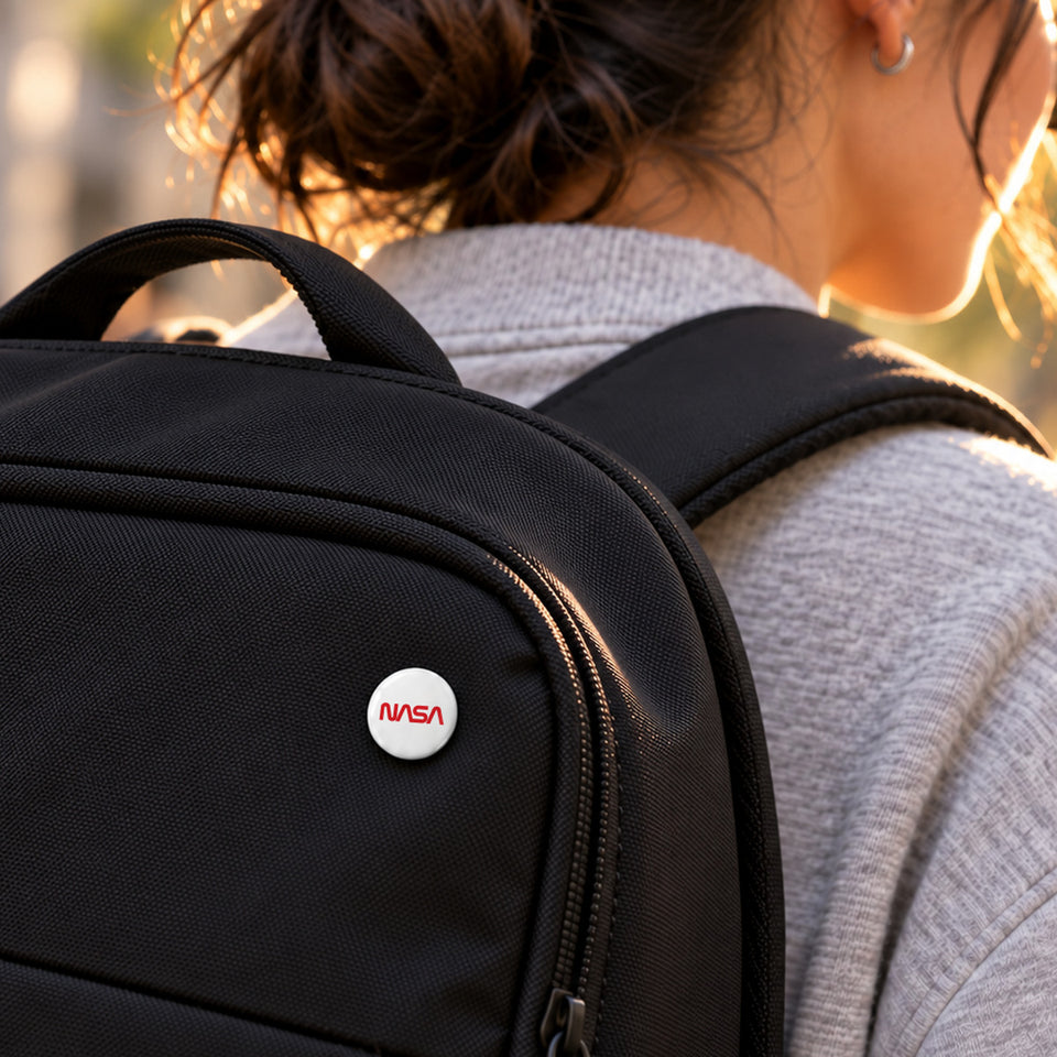 NASA worm 25 mm pin on a black backpack, worn on a city street