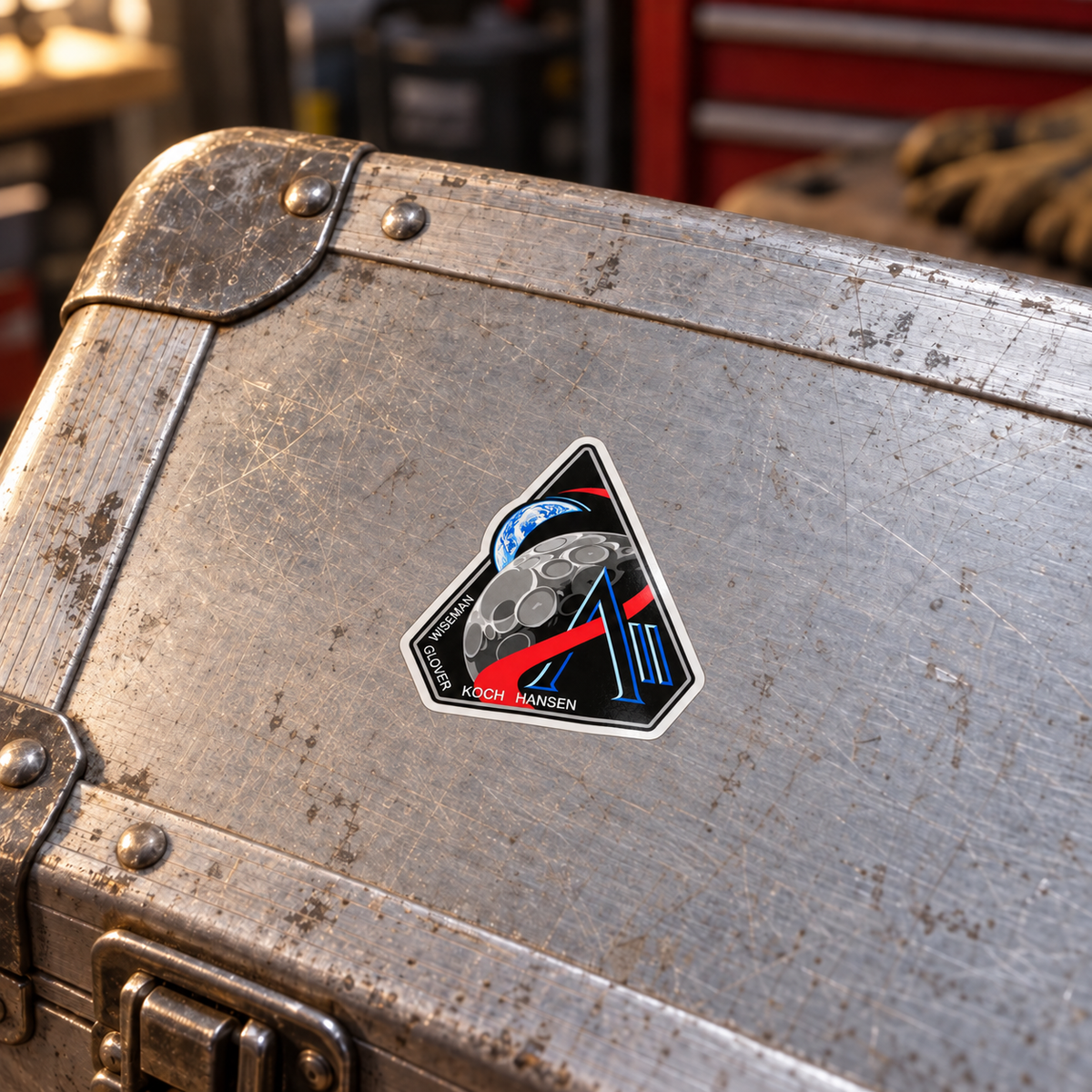 Artemis II mission badge vinyl sticker applied on a worn aluminium flight case in a workshop