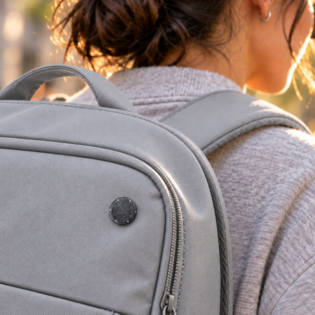 Orion heat shield 25 mm pin on a light grey backpack, worn on a city street