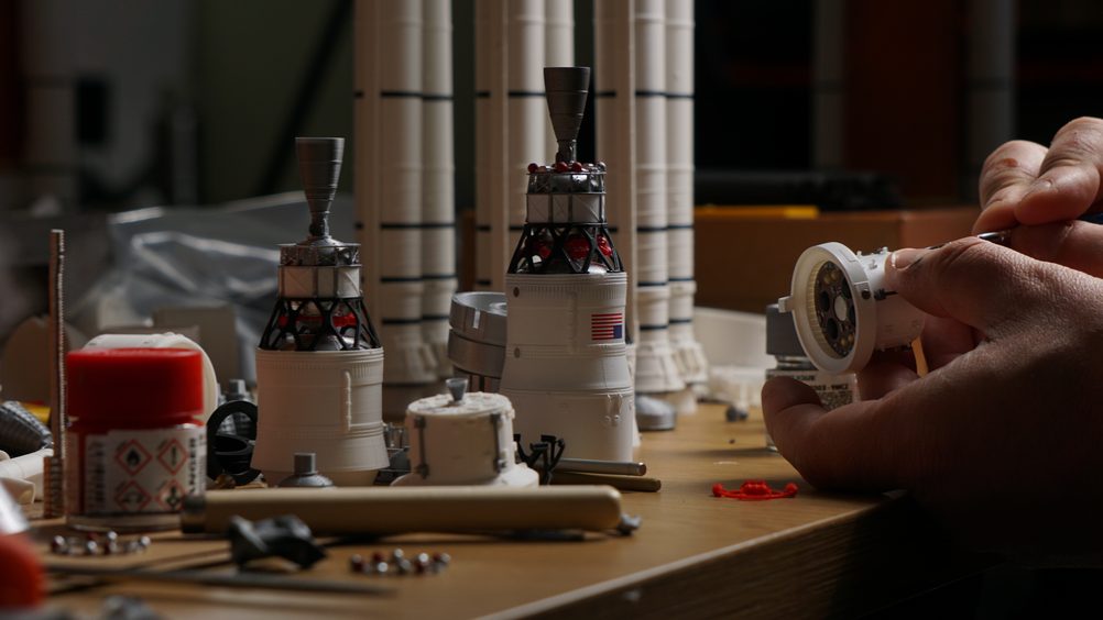 The workshop bench: two Orion capsules being assembled, SLS boosters behind them